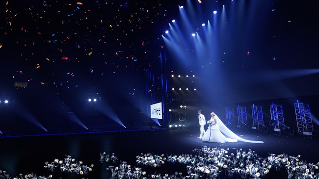 サプライズで開催された丸山桂里奈さんと本並健治さんの本物の結婚式でのXR技術を駆使した映像演出。新郎新婦が登場すると周囲に純白の花が広がり、クライマックスでは巨大なクリスタルのチャペルが出現。空には花火やオーロラやお祝いのランタンが広がるという映像演出
