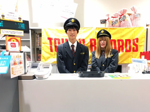 ことでん制服を着てレジカウンターに立つタワーレコード高松丸亀町店のスタッフ